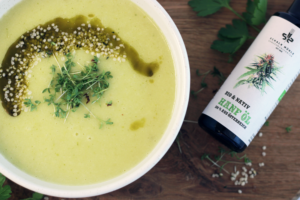 Cremige Kartoffel-Sellerie-Suppe mit Hanfsamen und Kresse, daneben Schalk Mühle Hanföl-Flasche