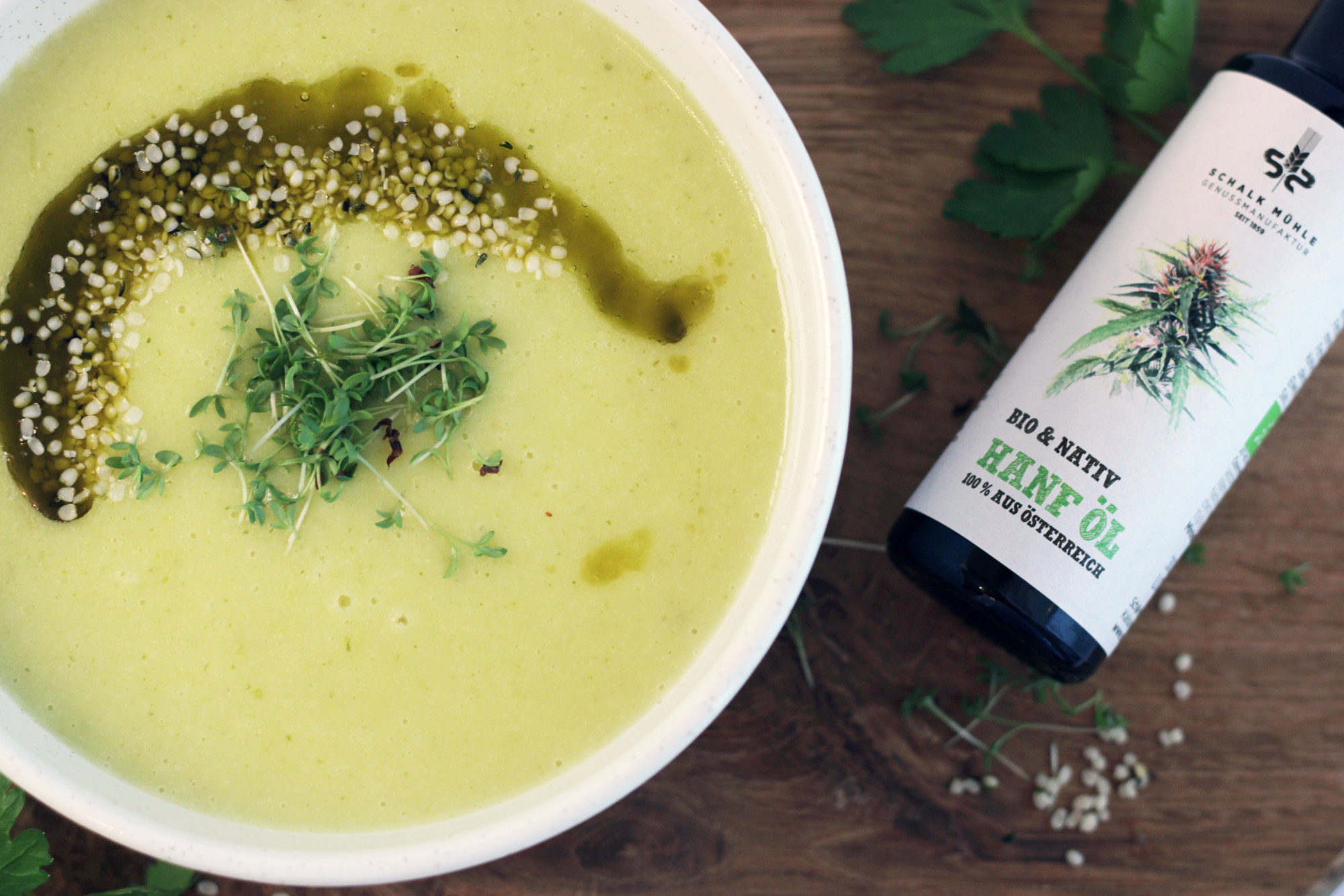 Cremige Kartoffel-Sellerie-Suppe mit Hanfsamen und Kresse, daneben Schalk Mühle Hanföl-Flasche
