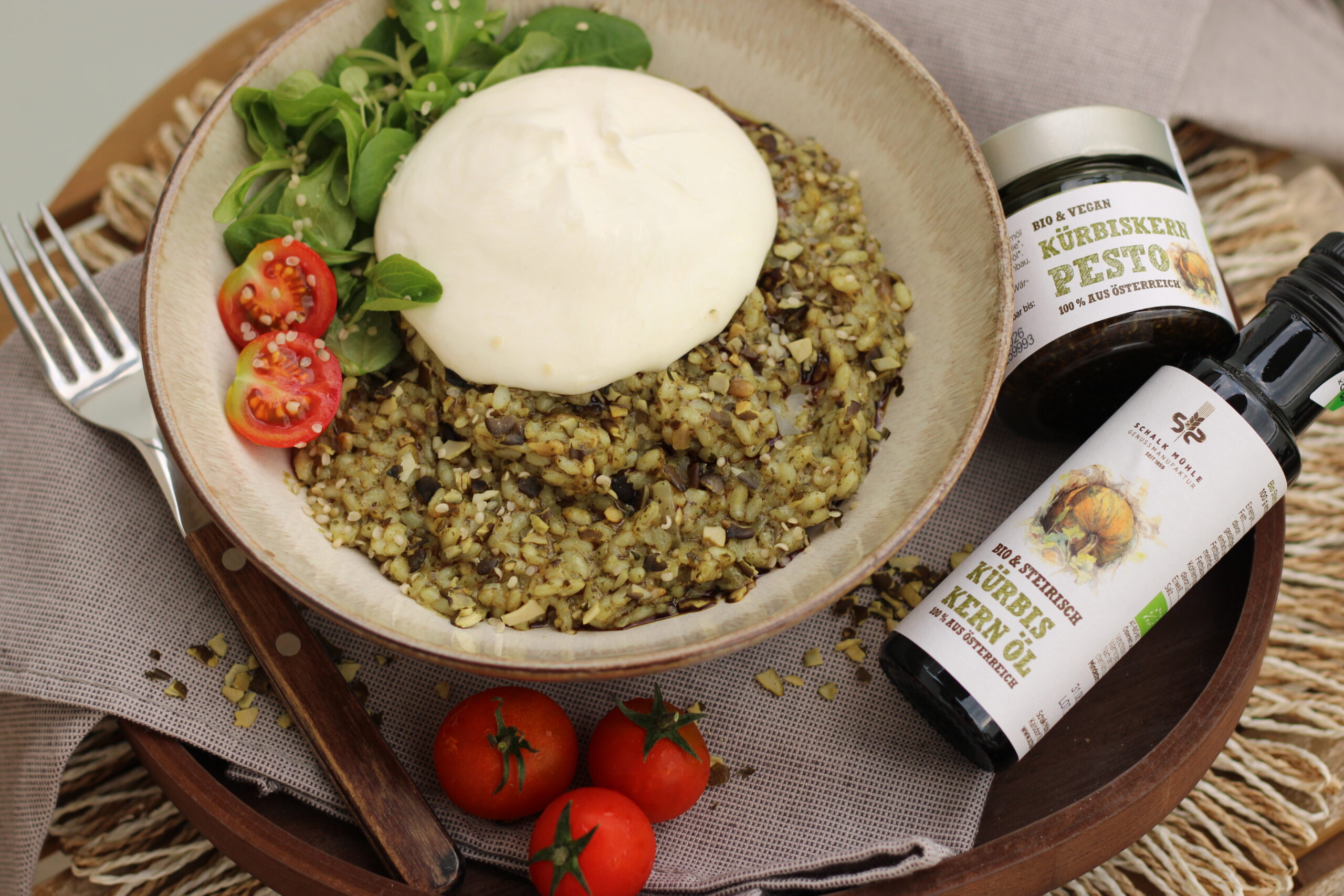 Kürbiskern-Risotto mit Burrata, Kirschtomaten und Vogerlsalat neben Schalk Mühle Kürbiskern-Pesto und Kürbiskernöl