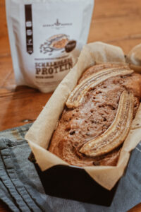 Bananenbrot mit karamellisierten Bananen in der Backform, dazu Schalk Mühle Schalkolade-Protein