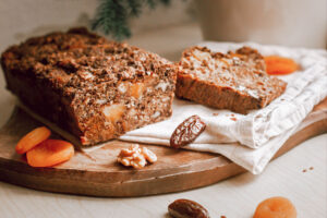 Angeschnittenes Früchtebrot mit Nüssen, getrockneten Marillen und Datteln auf einem Holzbrett