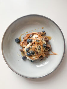 Protein-Waffel mit Joghurt, Heidelbeeren, Kernen und Erdnussmus in einer grauen Schale