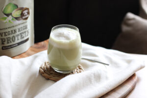 Matcha-Latte mit Milchschaum im Glas, daneben Schalk Mühle Vegan High Protein Matcha Power