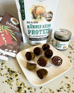Kürbiskern-Pralinen mit Schokolade auf einem Teller neben Schalk Mühle Kürbis Kern Protein und Kürbiskern Mus