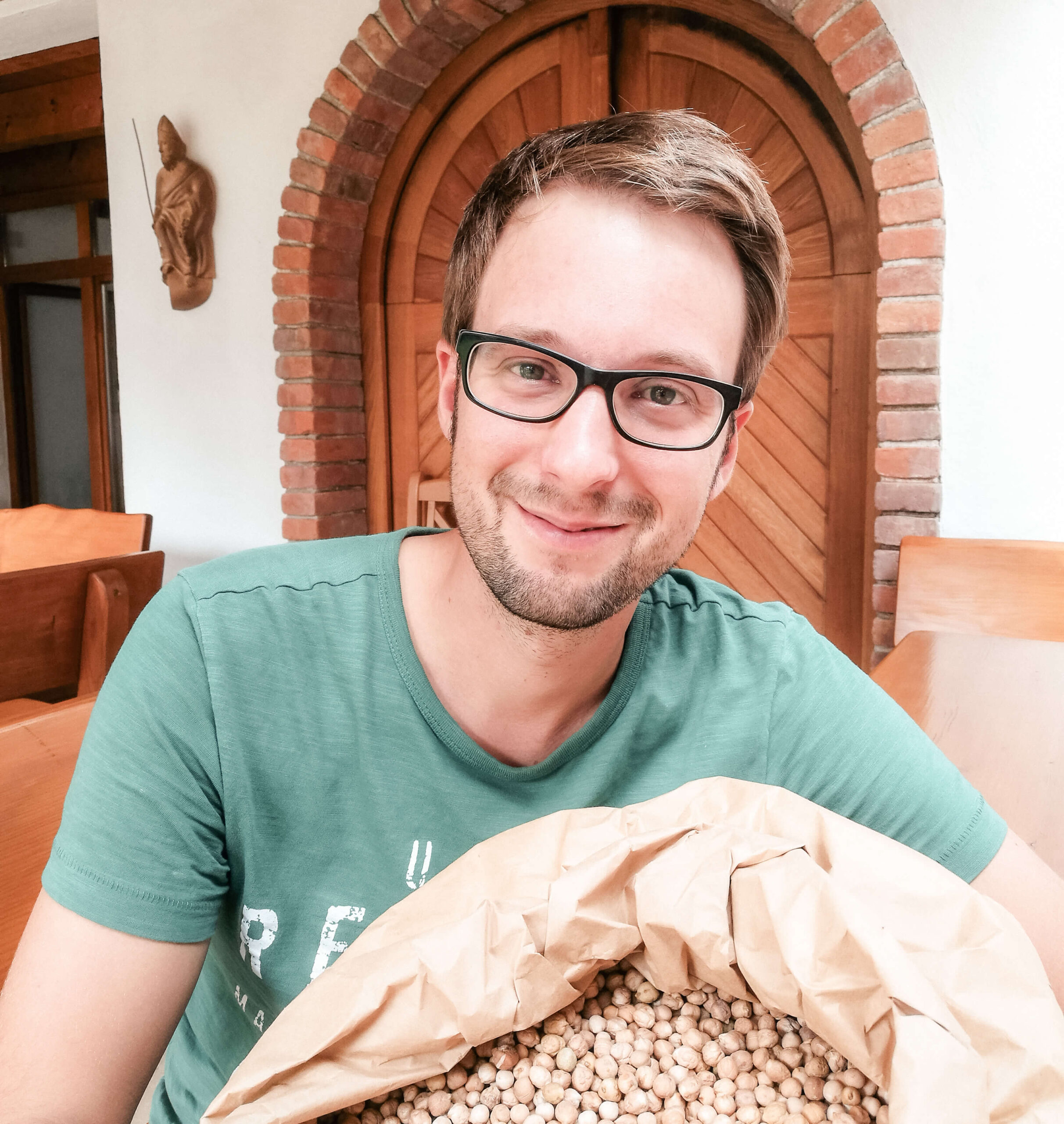 BIO Partner-Landwirt der Schalk Mühle Mark Koller mit einem Sack Kichererbsen vor seinem Hofgebäude.