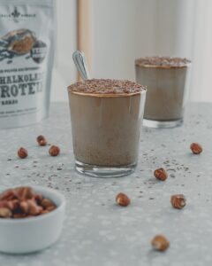 Zwei Gläser Schoko-Haselnuss-Pudding mit Raspelschokolade, dazu Schalk Mühle Schalkolade-Protein
