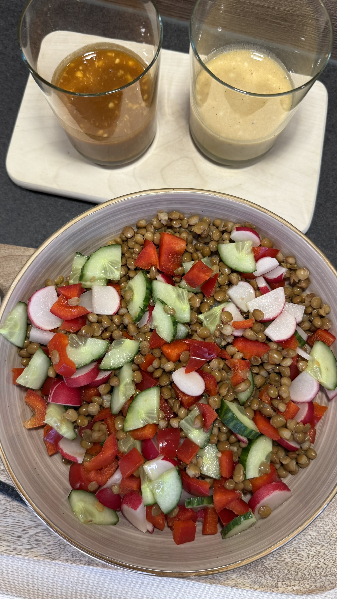 Bunter Linsensalat mit Gurke, Paprika und Radieschen, dazu zwei Dressings in Gläsern