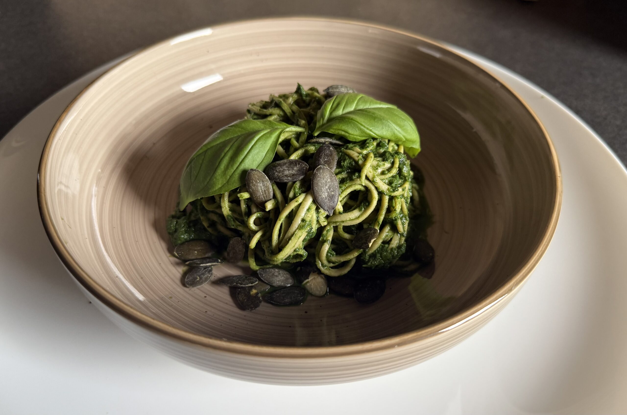 Grüne Pesto-Spaghetti in Schale mit Kürbiskernen und frischem Basilikum