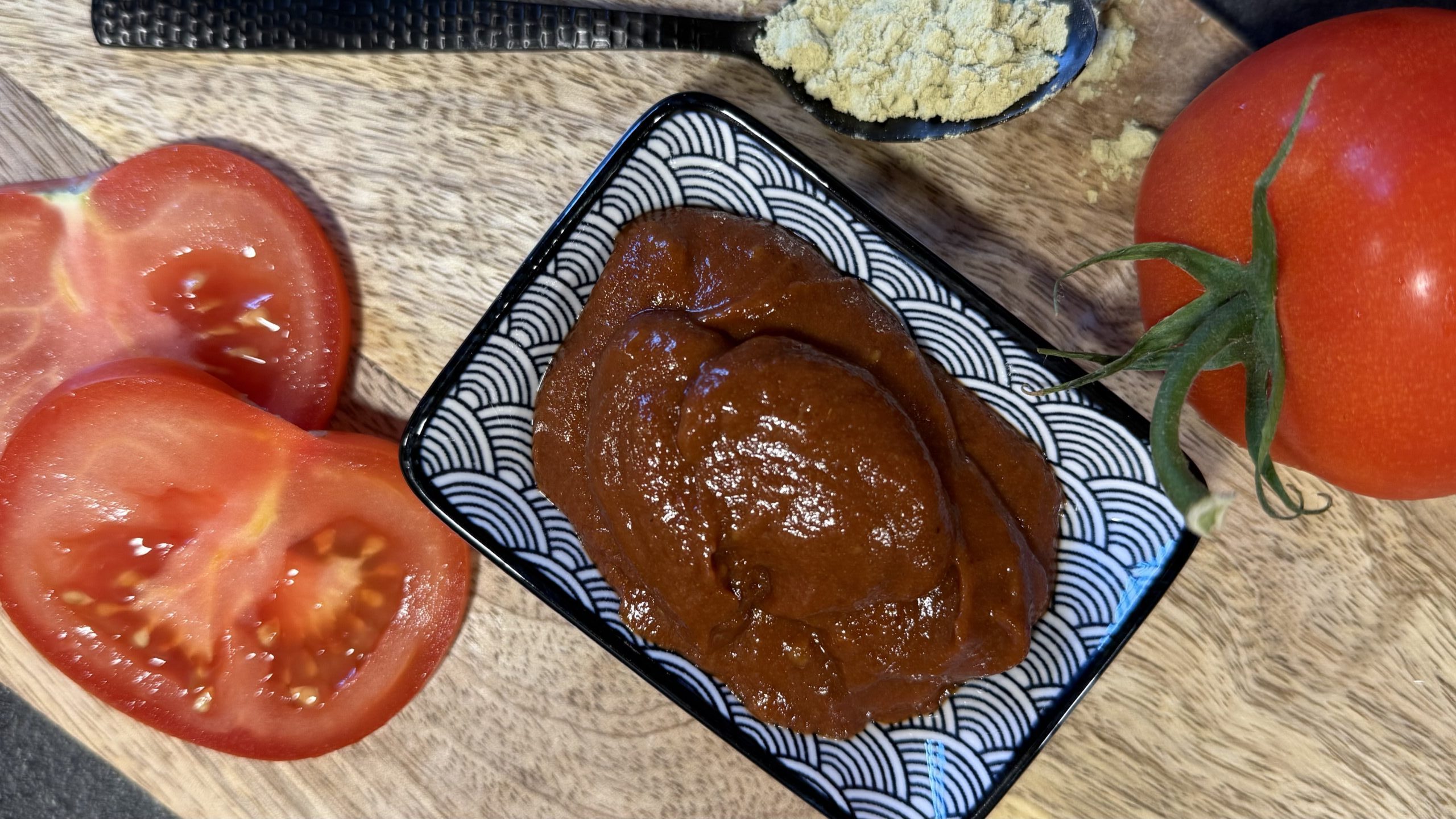 Selbstgemachte Tomatensauce im Schälchen mit frischen Tomaten und einem Löffel Proteinpulver