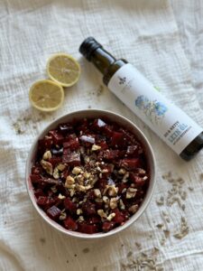 Rote-Bete-Salat mit Walnüssen und Kernen in Schale, daneben Schalk Mühle Leinöl und Zitrone
