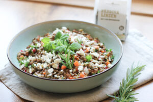 Linsensalat mit Feta, Karotten, Radieschen und frischen Kräutern in einer Schale, dahinter Schalk Mühle Pardina Linsen