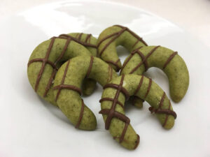 Grüne Kürbiskern-Kipferl mit Schokoladenstreifen auf einem weißen Teller