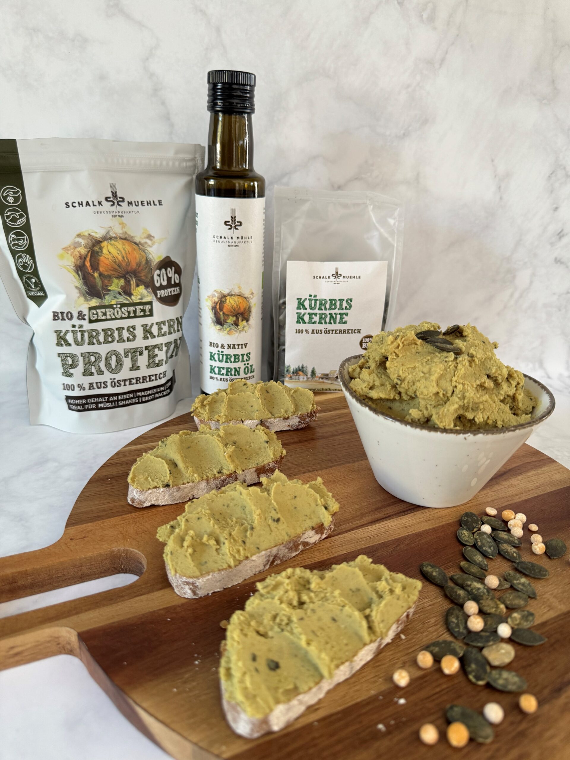Kürbiskern-Aufstrich auf Brot und in Schale, dazu Schalk Mühle Kürbiskernprotein, Kürbiskernöl und Kürbiskerne