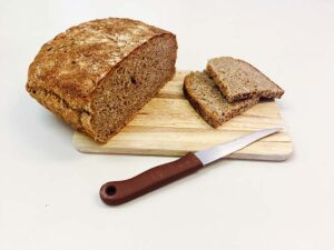 Angeschnittenes Leinsamen-Vollkornbrot auf einem Holzbrett mit Messer