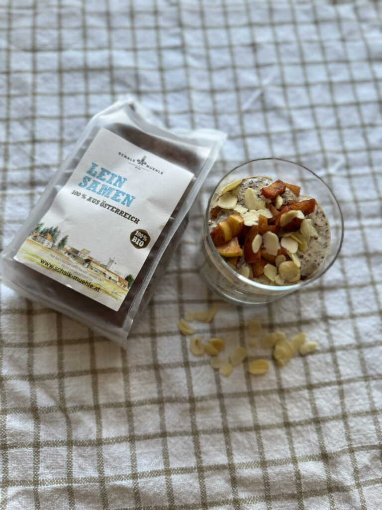 Leinsamen-Pudding im Glas mit Zimtapfel und Mandelblättchen, daneben Schalk Mühle Leinsamen