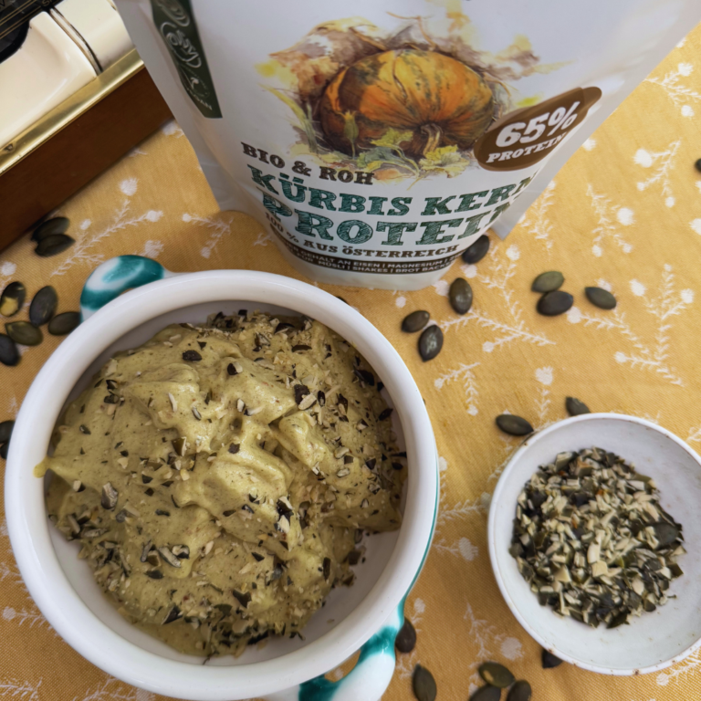 Grünes Kürbiskern-Nicecream mit gehackten Kürbiskernen in einer Schale neben Schalk Mühle Kürbis Kern Protein
