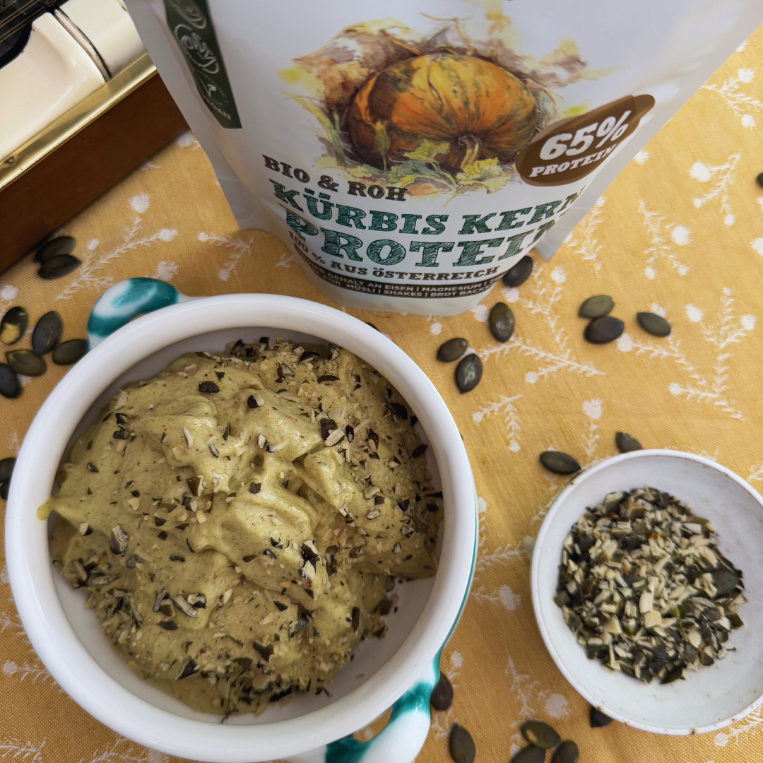 Grünes Kürbiskern-Nicecream mit gehackten Kürbiskernen in einer Schale neben Schalk Mühle Kürbis Kern Protein