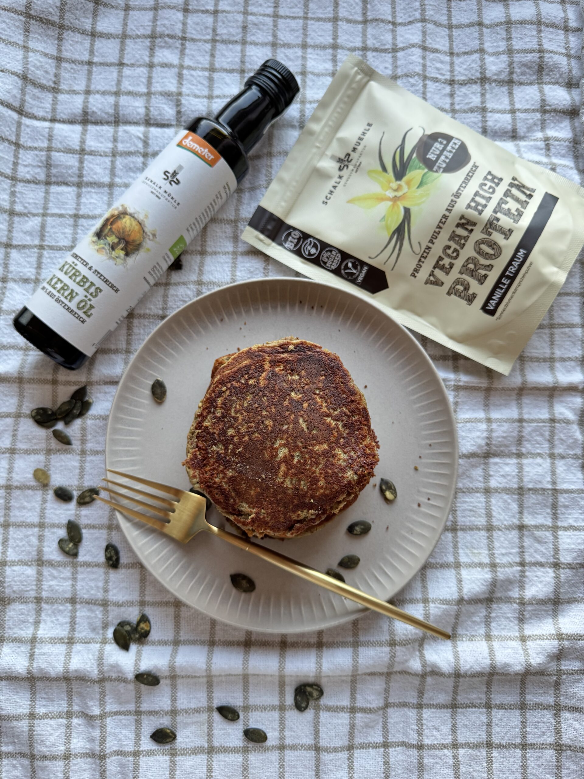 Protein-Pancake mit Schalk Mühle Kürbiskernöl, veganem Vanille-Proteinpulver und Kürbiskernen auf Teller