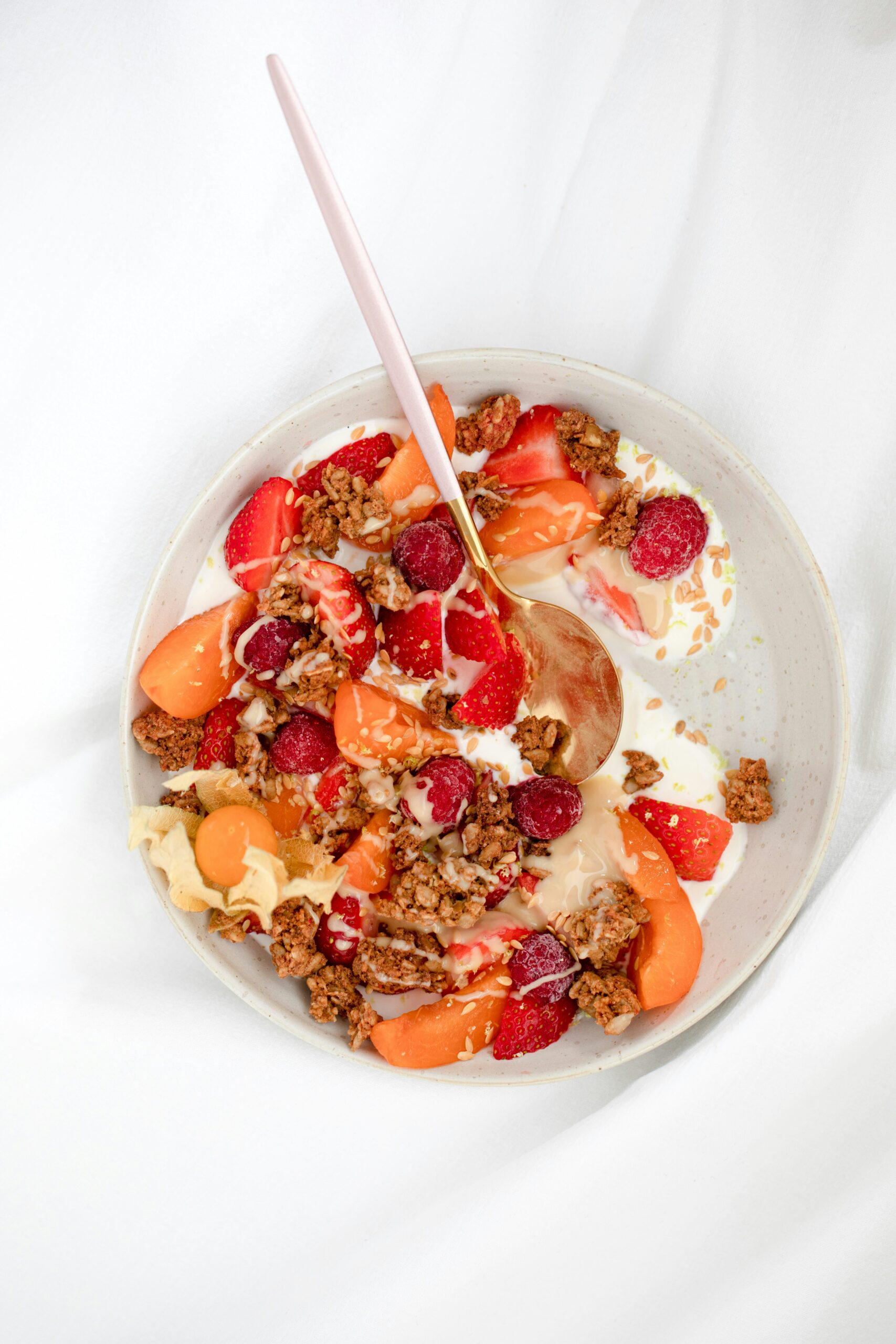 Frühstücksbowl mit Joghurt, Erdbeeren, Himbeeren, Marille und Granola von oben