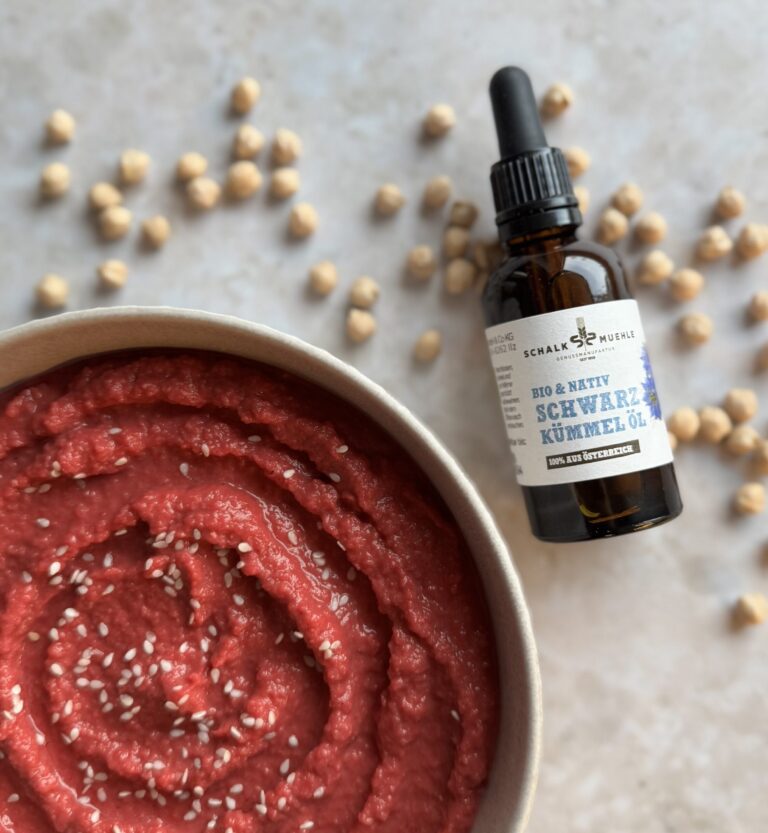 Pinker Rote-Rüben-Hummus mit Sesam und Kichererbsen neben Schalk Mühle Schwarzkümmelöl
