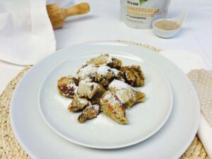 Kaiserschmarren mit Staubzucker auf einem Teller, daneben Sonnenblumen-Proteinpulver