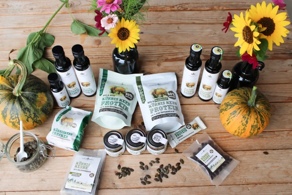 Schalk Mühle product range with pumpkin seed oil, protein, and kernels on a wooden table with sunflowers
