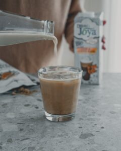 Milch wird in ein Glas mit eisgekühltem Schalkochino-Kaffeedrink gegossen