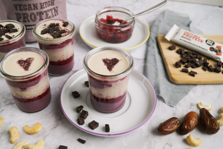 Veganes Schichtdessert im Glas mit Beeren, Vanillecreme und Aronia-Herz, dazu Schalk Mühle Vegan High Protein