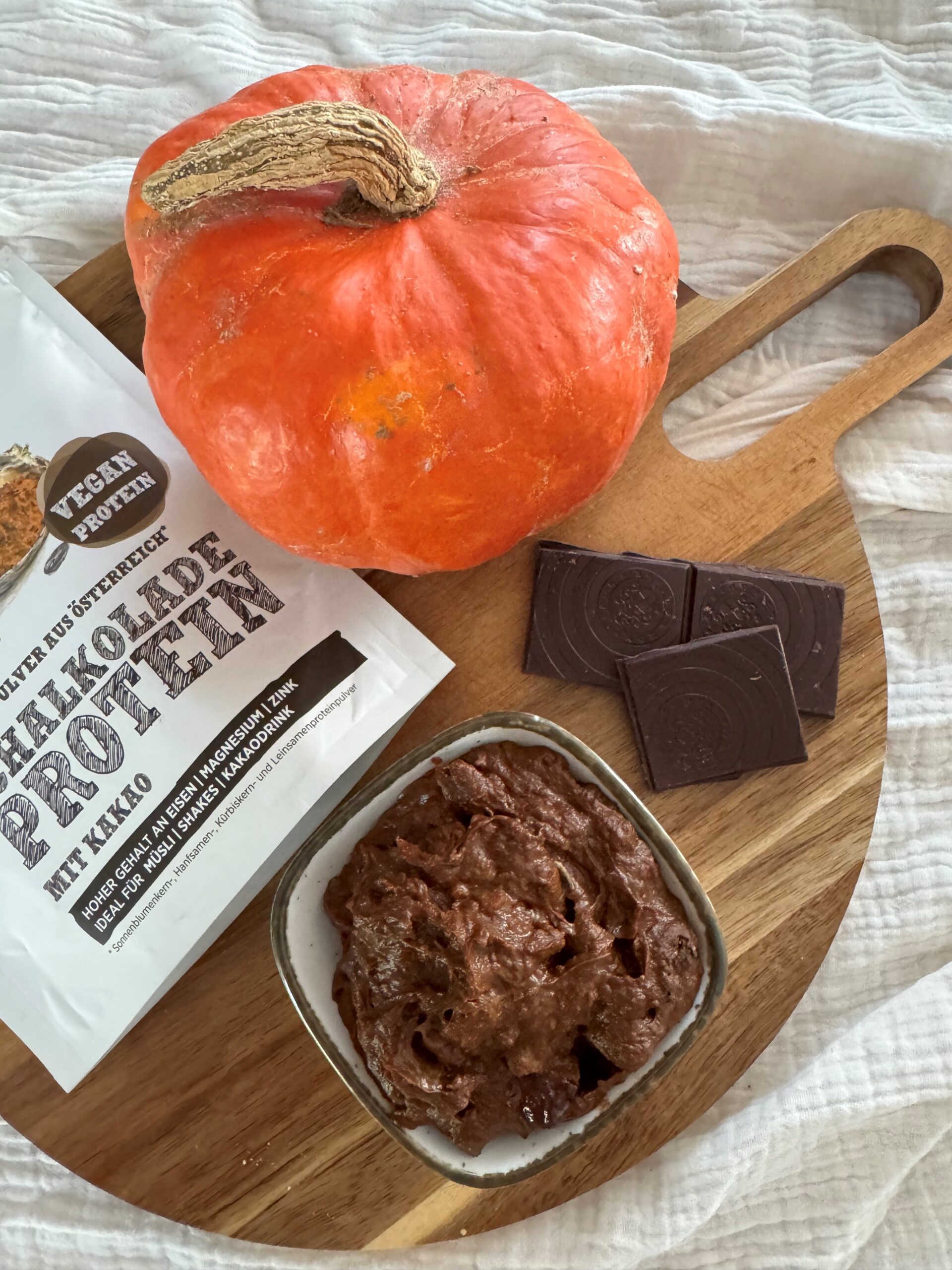 Schoko-Kürbis-Creme in Schale mit Hokkaido und dunkler Schokolade, daneben Schalk Mühle Protein mit Kakao