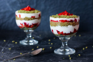Steiramisu in zwei Gläsern: Schichten aus Creme, Erdbeeren und grünem Kürbiskern-Streusel