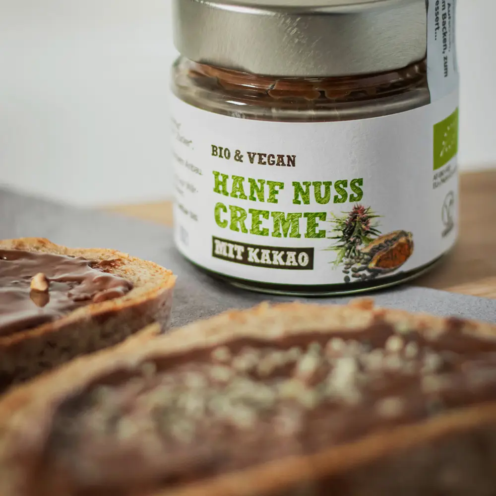 Schalk Mühle Bio Hanf-Nuss-Creme mit Kakao, daneben zwei Brote mit der Schoko-Creme bestrichen