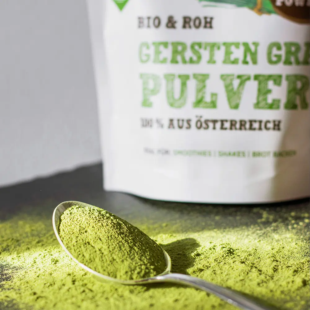 Löffel mit grünem Schalk Mühle Bio Gersten-Gras-Pulver vor dem Produktbeutel
