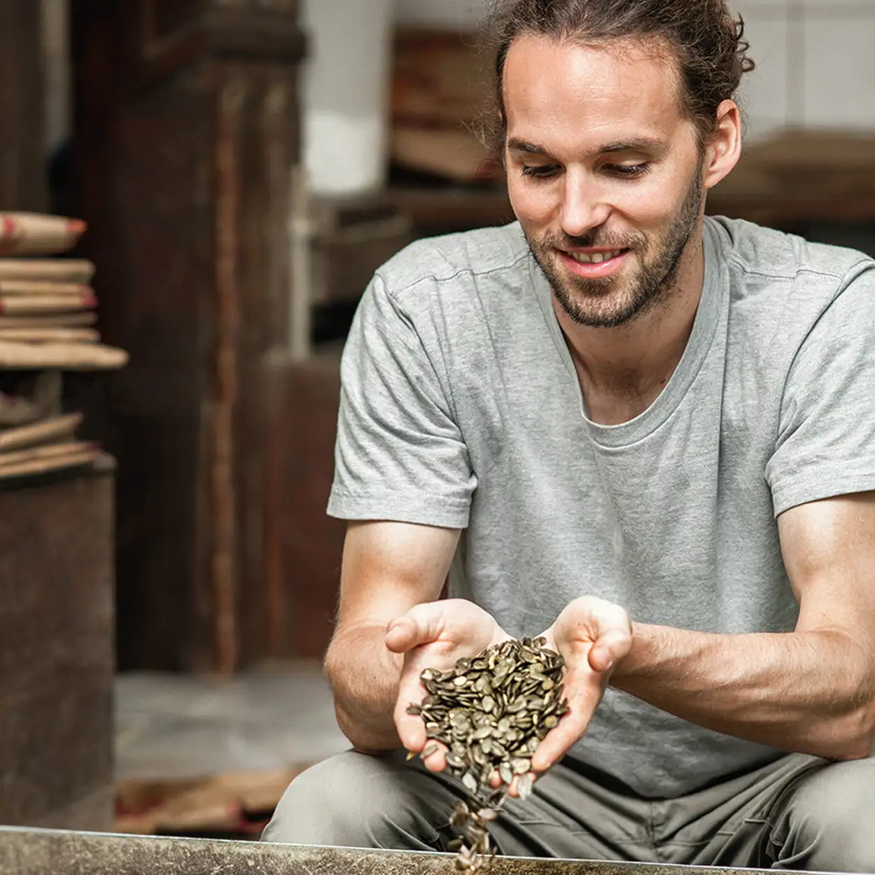 Lächelnder Mann hält eine Handvoll Kürbiskerne in der Schalk Mühle