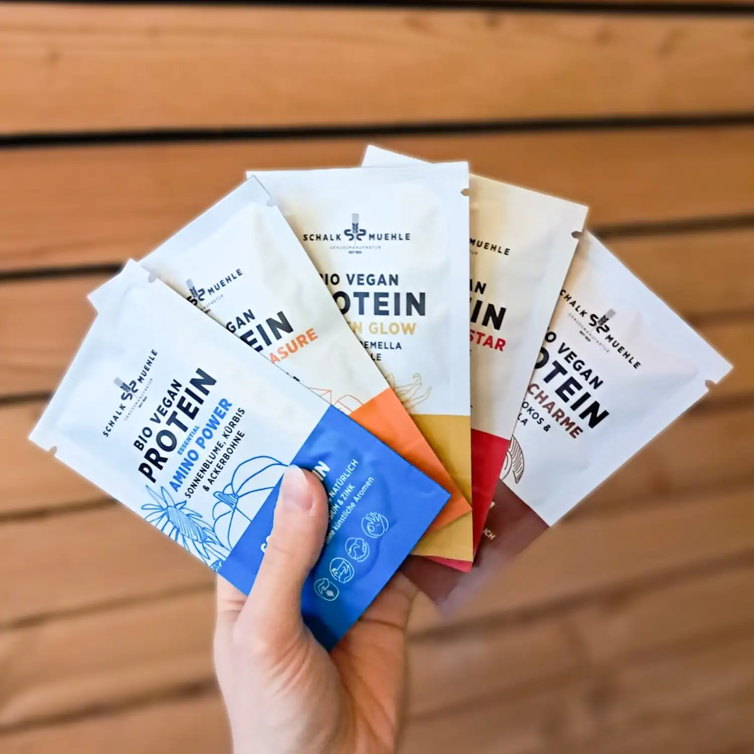 Hand hält fünf Schalk Mühle Bio Vegan Protein Probiersackerl in verschiedenen Sorten aufgefächert