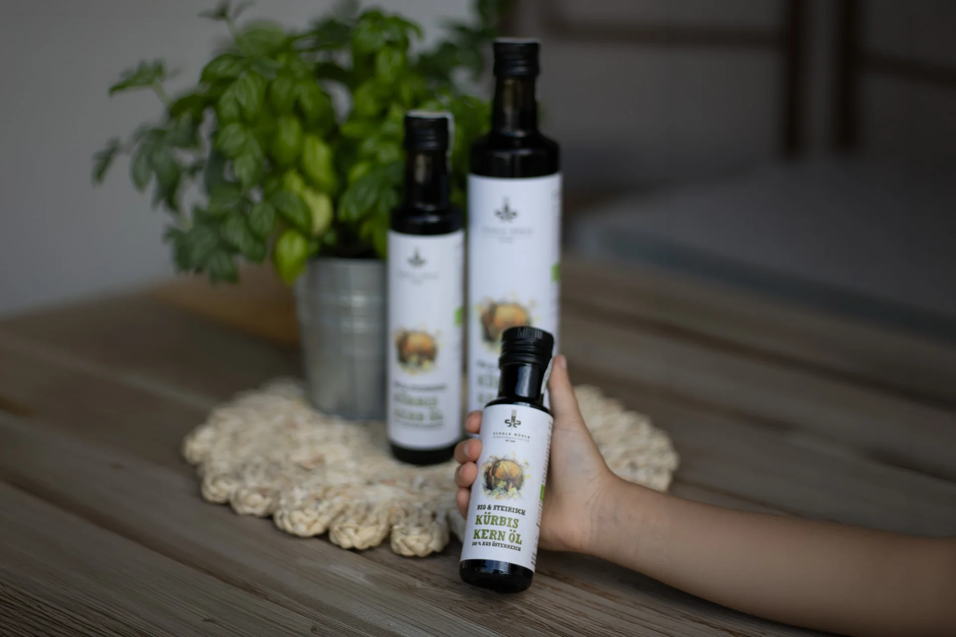 Schalk Mühle Organic & Styrian pumpkin seed oil in several bottle sizes, a hand holding the small bottle
