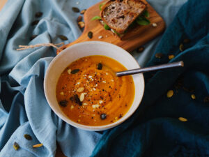 Cremige Kürbissuppe mit Kürbiskernen und Pfeffer, dazu ein belegtes Vollkornbrot