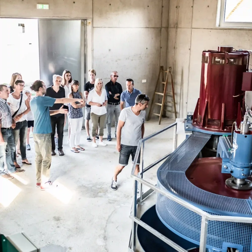 Besuchergruppe betrachtet bei einer Führung die moderne Turbine im Wasserkraftwerk der Schalk Mühle